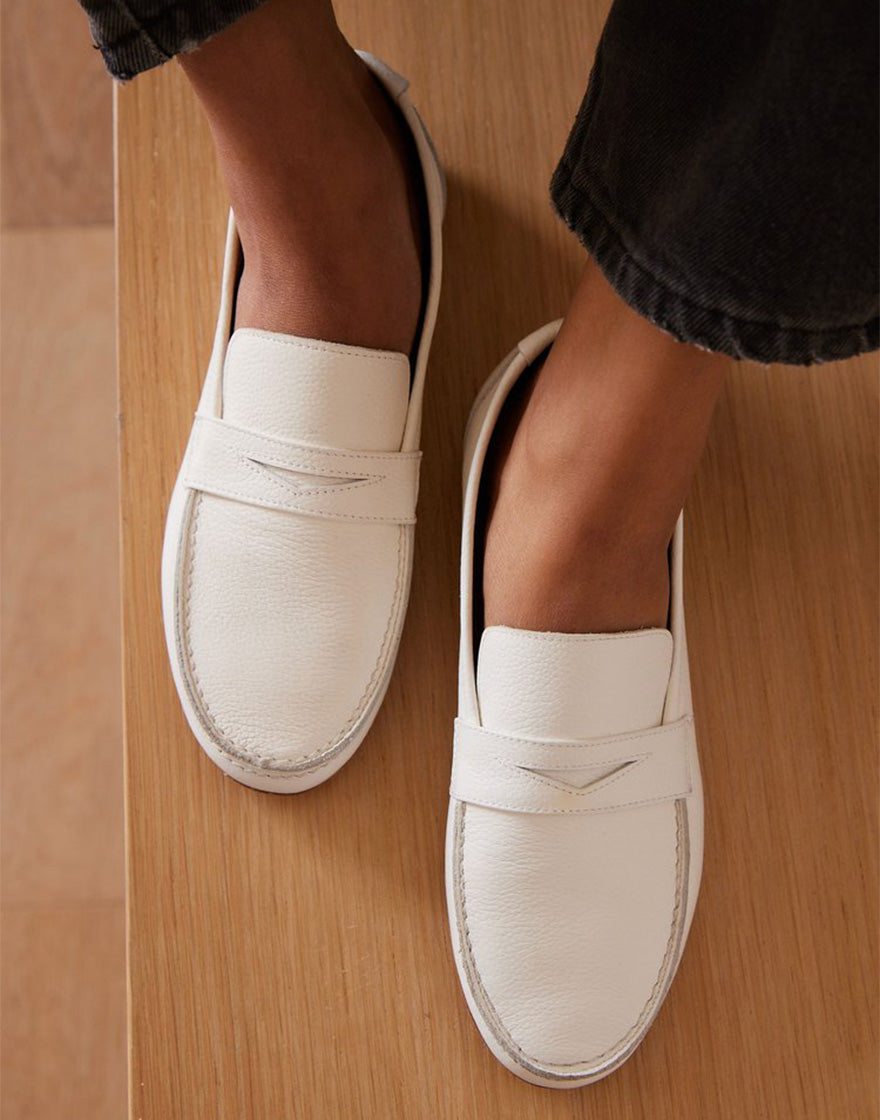 Overhead image of person wearing white soft leather loafers with simple stitching